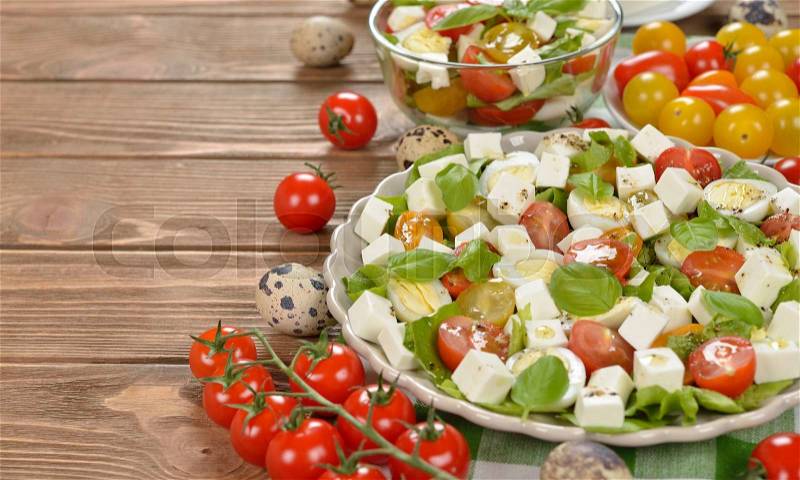 Vegetarian salad with cherry tomatoes, eggs and cheese on brown background, stock photo