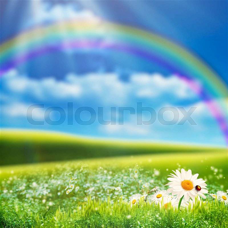 Dreamy natural landscape with green hills under blue skies and funny rainbow, stock photo