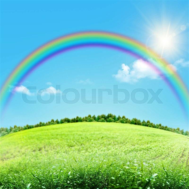 Dreamy natural landscape with green hills under blue skies and funny rainbow, stock photo