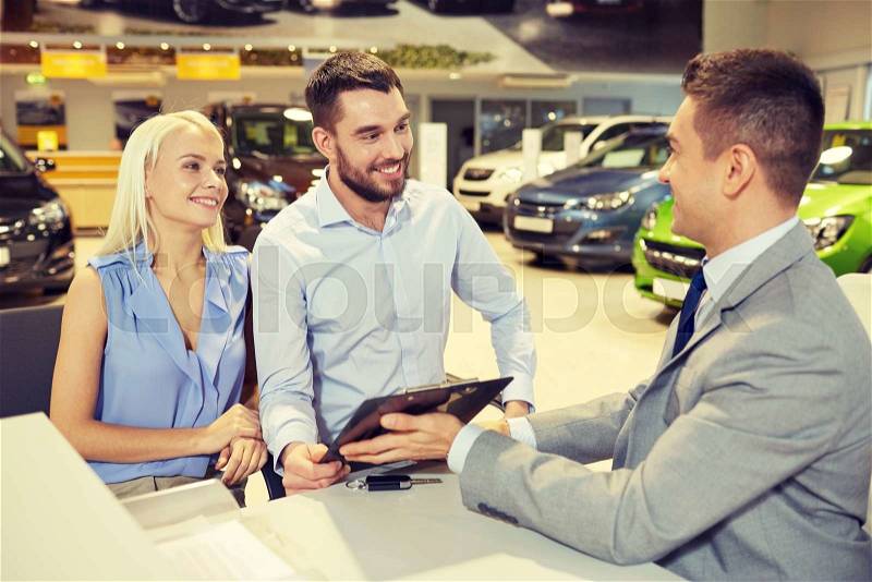 Auto business, sale and people concept - happy couple with dealer buying car in auto show or salon, stock photo