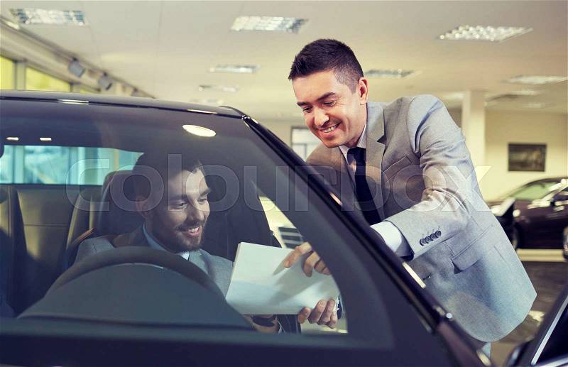 Auto business, sale and people concept - happy man with dealer buying car in auto show or salon, stock photo