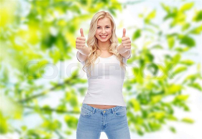 Emotions, expressions, advertisement and people concept - happy smiling young woman or teenage girl in white t-shirt showing thumbs up with both hands over green natural background, stock photo