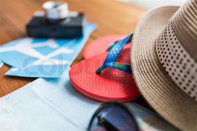 Summer vacation, tourism and objects concept - close up of travel map, airplane tickets, flip-flops and hat, stock photo
