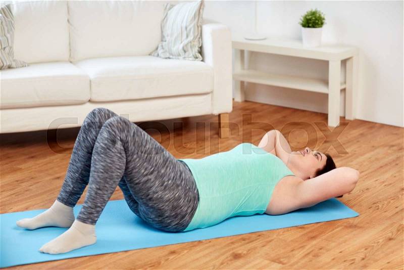 Fitness, sport, people and healthy lifestyle concept - plus size young woman exercising on mat at home, stock photo