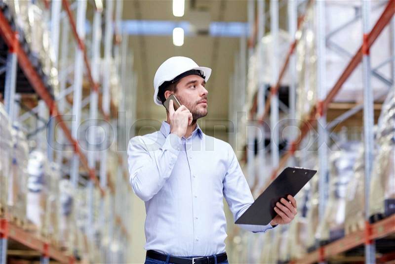 Wholesale, logistic, business, export and people concept - businessman with clipboard calling on smartphone at warehouse, stock photo