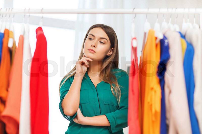 Clothing, fashion, style and people concept - woman choosing clothes at home wardrobe, stock photo