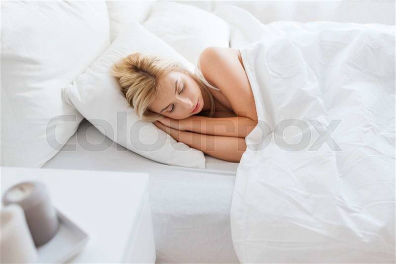 Rest, comfort and people concept - young woman sleeping in bed at home bedroom, stock photo