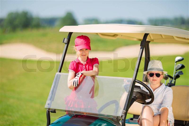 Two girls walking in golf car at golf course at summer day, stock photo