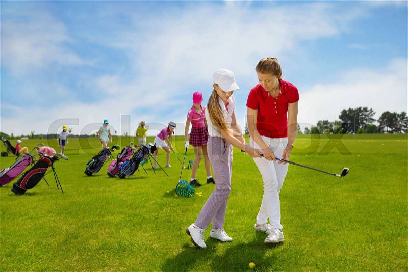 Kids practicing hits with trainer at golf school at summer day, stock photo