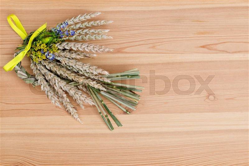 Bundle of wheat with flower and band on the wooden desk, stock photo