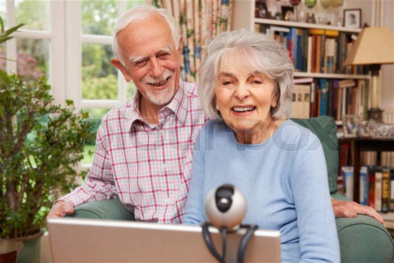 Senior Couple Using Laptop And Webcam To Talk To Family, stock photo