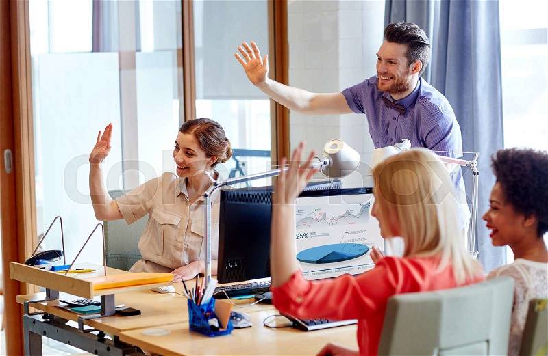 Business, startup and office concept - happy creative team waving hands in office, stock photo