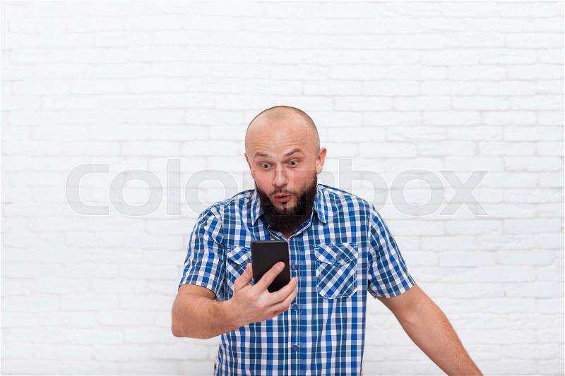 Casual Bearded Business Man Confused Surprised Holding Cell Smart Phone Office White Brick Wall, stock photo