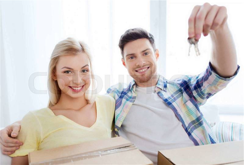 Home, people, repair and real estate concept - happy couple with key and boxes moving to new home, stock photo
