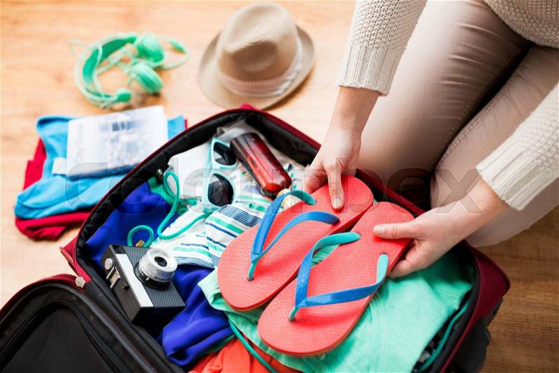 Summer vacation, travel, tourism and objects concept - close up of woman packing travel bag for vacation, stock photo