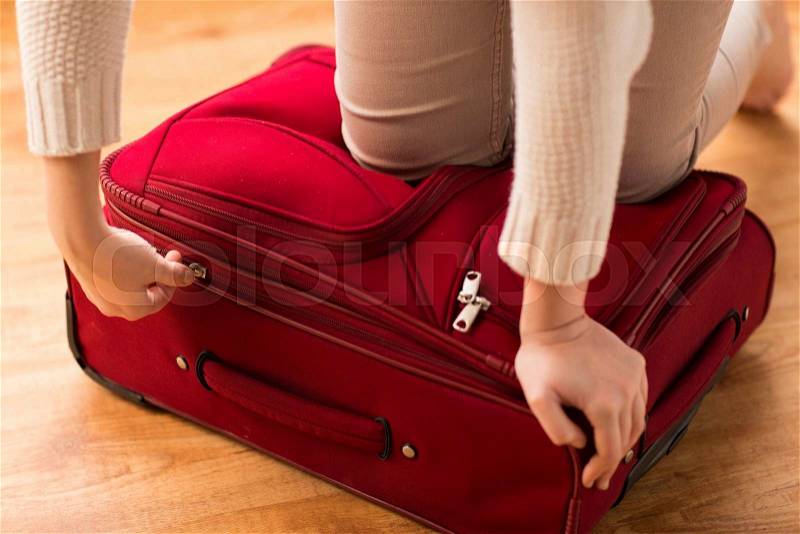 Summer vacation, travel, tourism and objects concept - close up of woman packing and zipping travel bag for vacation, stock photo