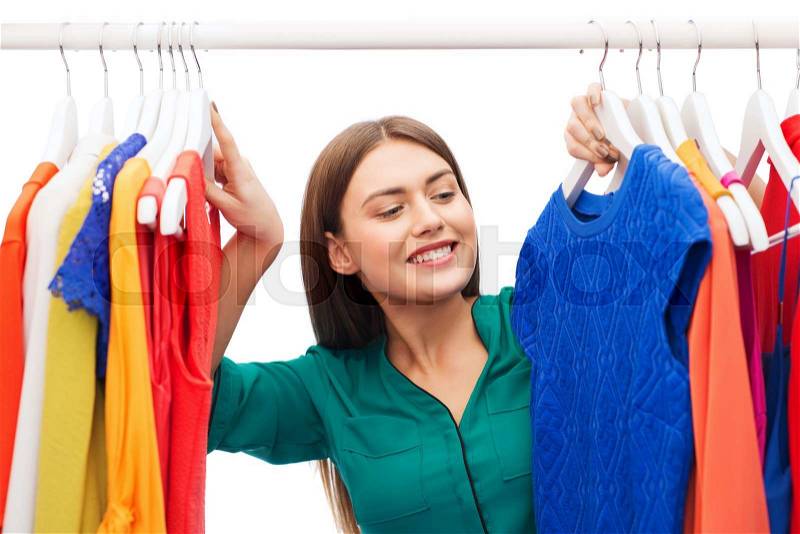 Clothing, fashion, style and people concept - happy woman choosing clothes at home wardrobe, stock photo