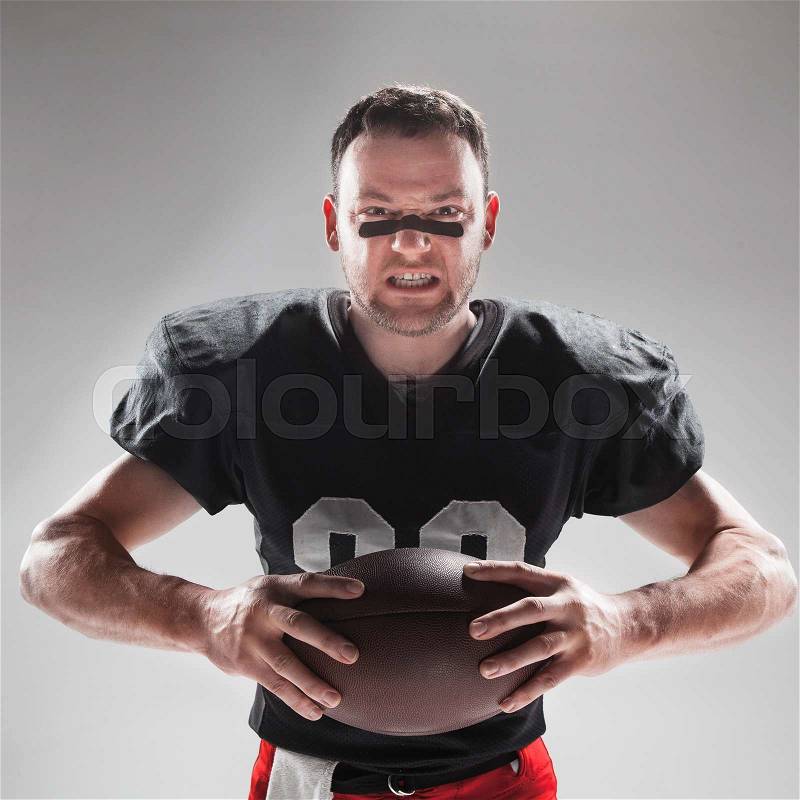 Caucasian fitness man as american football player holding a ball on white background, stock photo