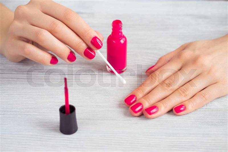 Female hands with red manicure holding cotton wool on a stick, stock photo