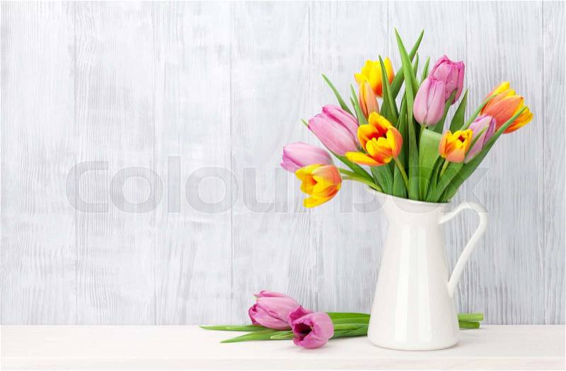 Fresh colorful tulip flowers bouquet on shelf in front of wooden wall. View with copy space, stock photo