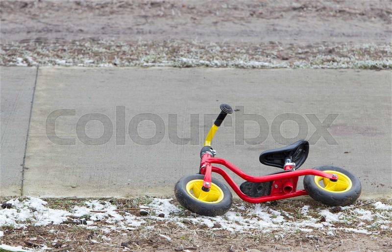 Red childrens balance bicycle at the side of the road, stock photo