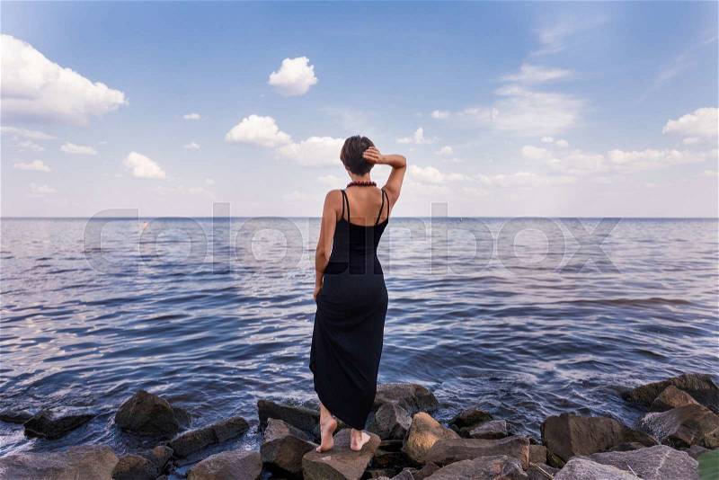 The Girl stand on stoned river bank on sky background, stock photo