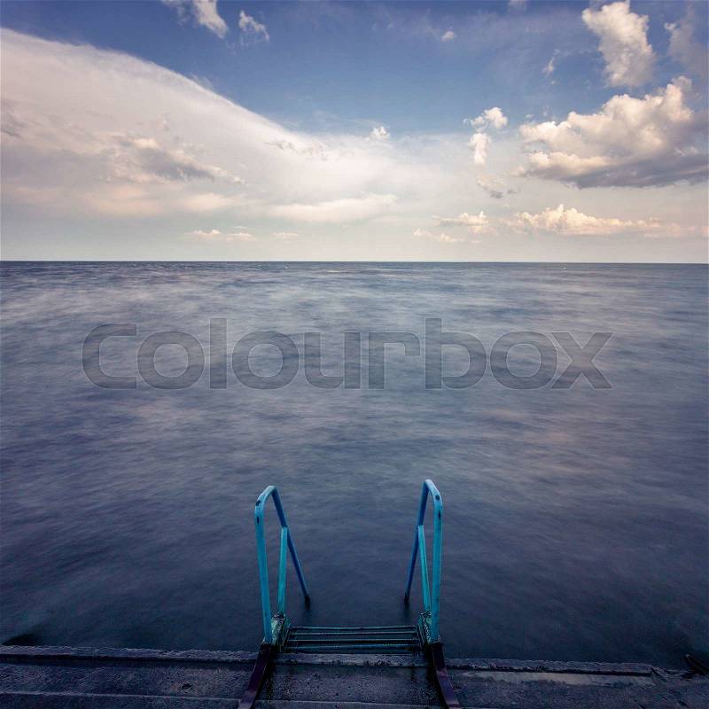The Avesome landscape view on a seaside with stairs into the water and cloudy sky on background, stock photo