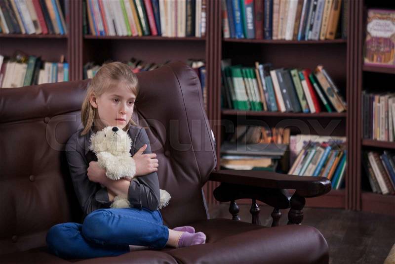 Depressed alone crying girl sitting with toy at room, stock photo