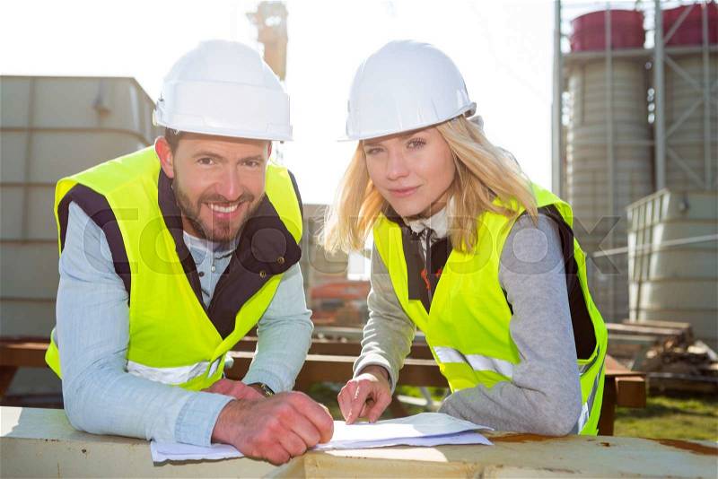 View of 2 Workers on a construction studying blueprints, stock photo