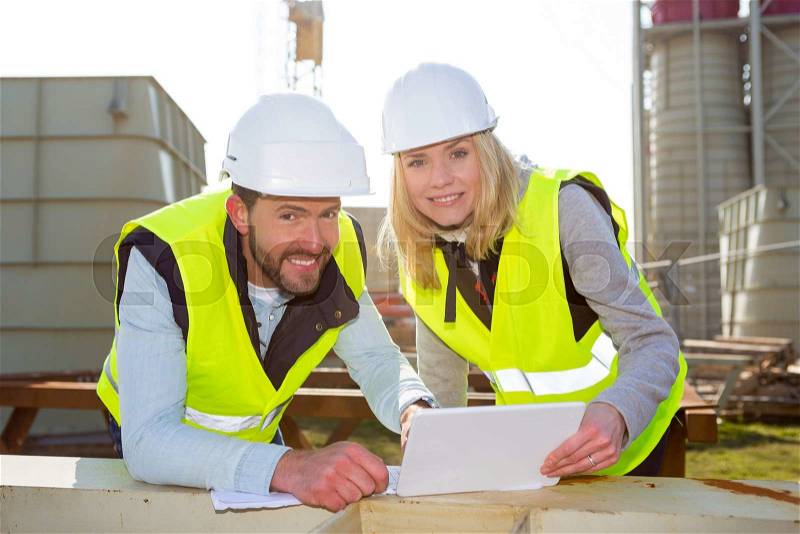 View of 2 Workers on a construction studying blueprints, stock photo