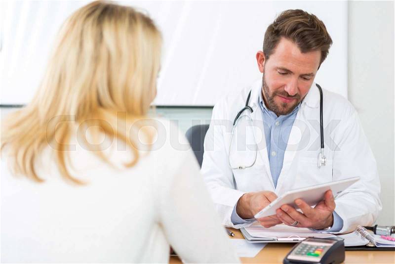 View of a Young doctor watching results on tablet to patient, stock photo