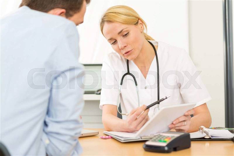 View of a Young woman doctor watching results on tablet to patient, stock photo