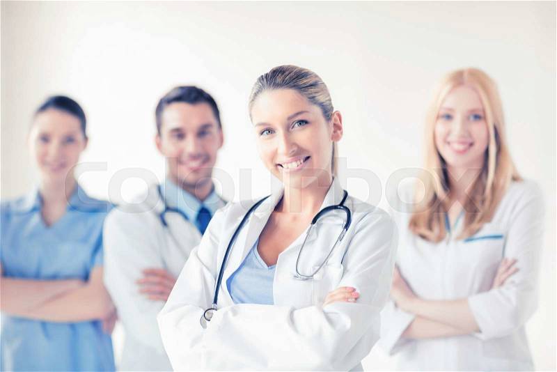 Attractive female doctor in front of medical group, stock photo