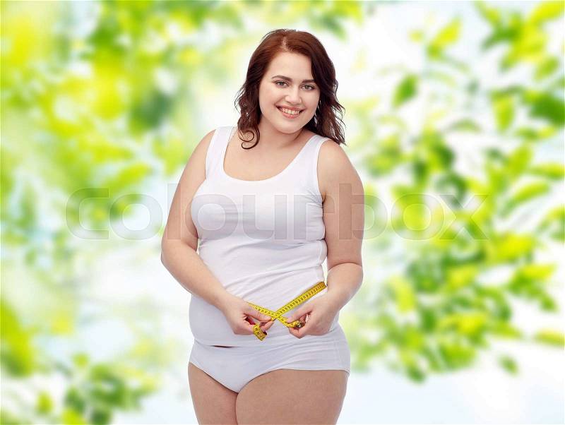 Weight loss, diet, slimming, size and people concept - happy young plus size woman in underwear measuring tape over green natural background, stock photo