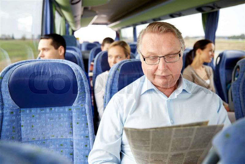 Transport, tourism, trip and people concept - senior man reading newspaper in travel bus, stock photo