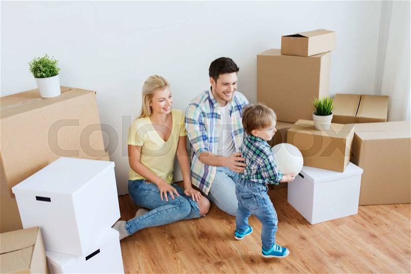Mortgage, people, housing, moving and real estate concept - happy family with boxes playing ball at new home, stock photo