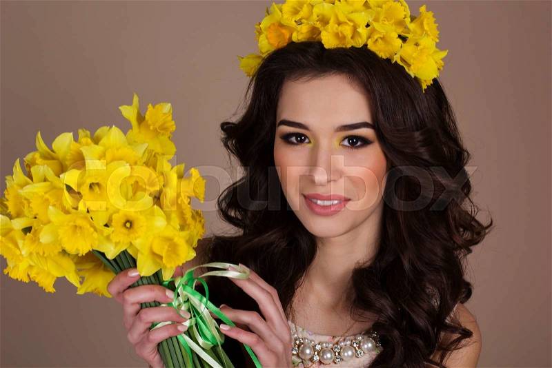 Closeup portrait of smiling beautiful woman with bouquet of yellow daffodils. Spring time, stock photo