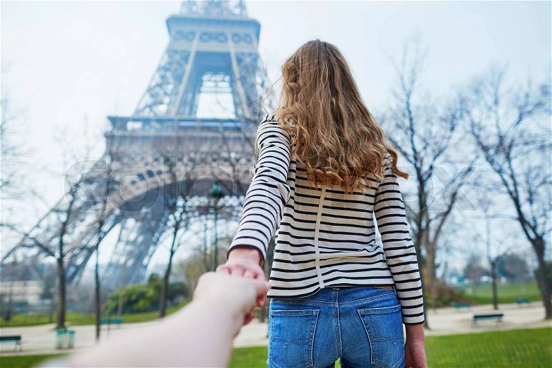 Beautiful young girl near the Eiffel tower, follow me concept, stock photo