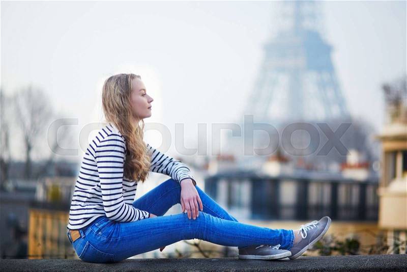 Beautiful young girl outdoors near the Eiffel tower in Paris, France, stock photo