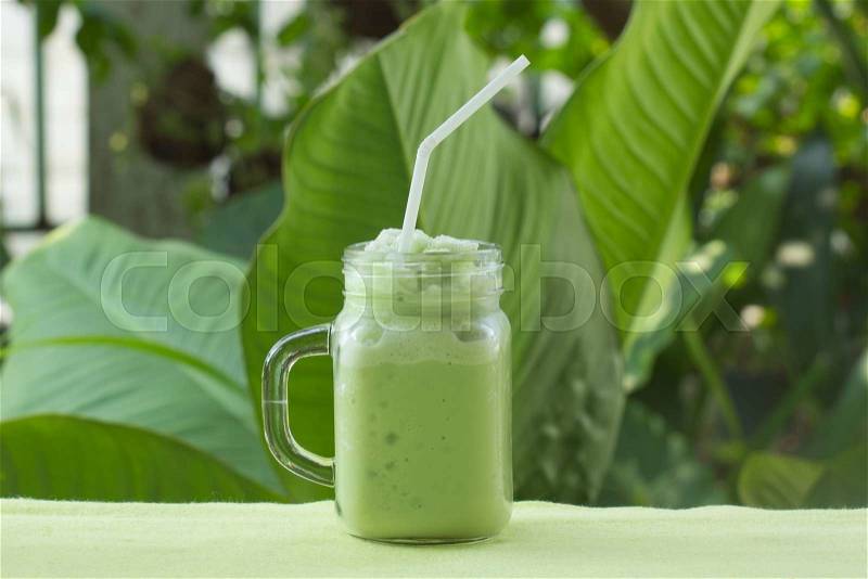 Matcha Green Tea smoothie for refreshment on garden background, stock photo