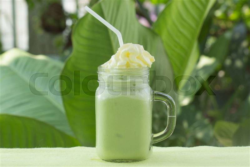 Matcha Green Tea smoothie with whiped cream for refreshment on garden background, stock photo