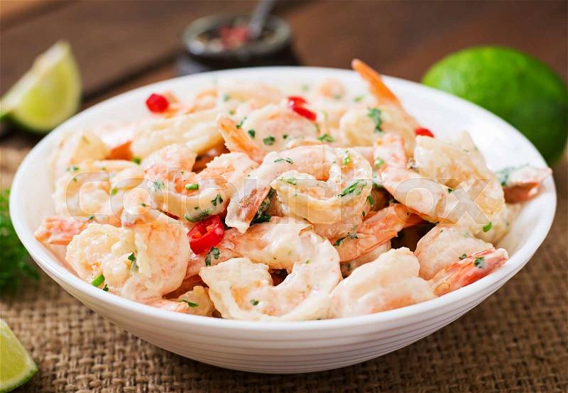 Shrimp in a creamy garlic sauce with parsley and lime in white bowl, stock photo