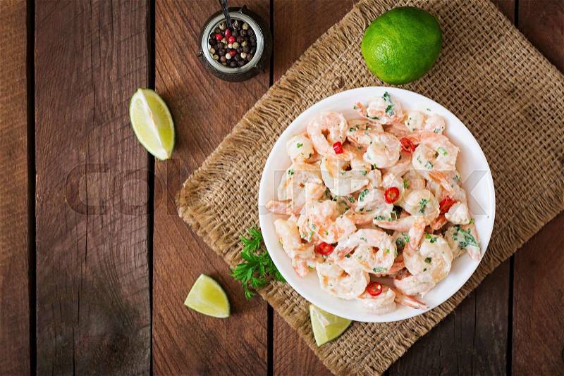 Shrimp in a creamy garlic sauce with parsley and lime in white bowl. Top view, stock photo