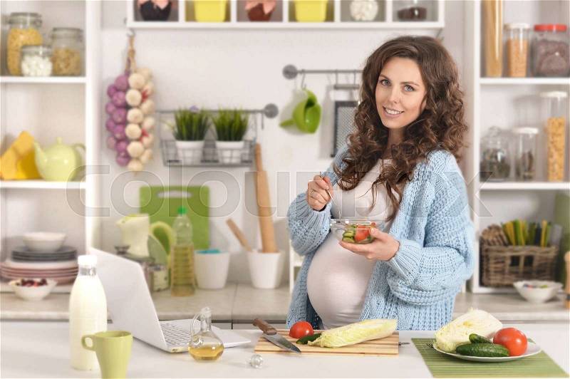 Beautiful pregnant woman with food at kitchen, stock photo