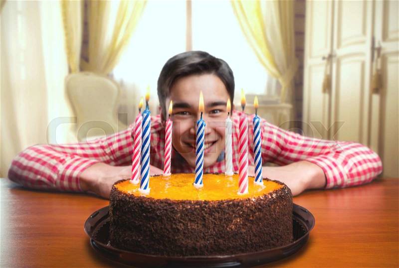 Happy birthday boy with a cake with candles in decorated room, stock photo