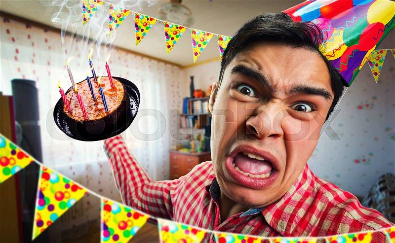 Crazy birthday boy with cake in his hand in decorated room, stock photo