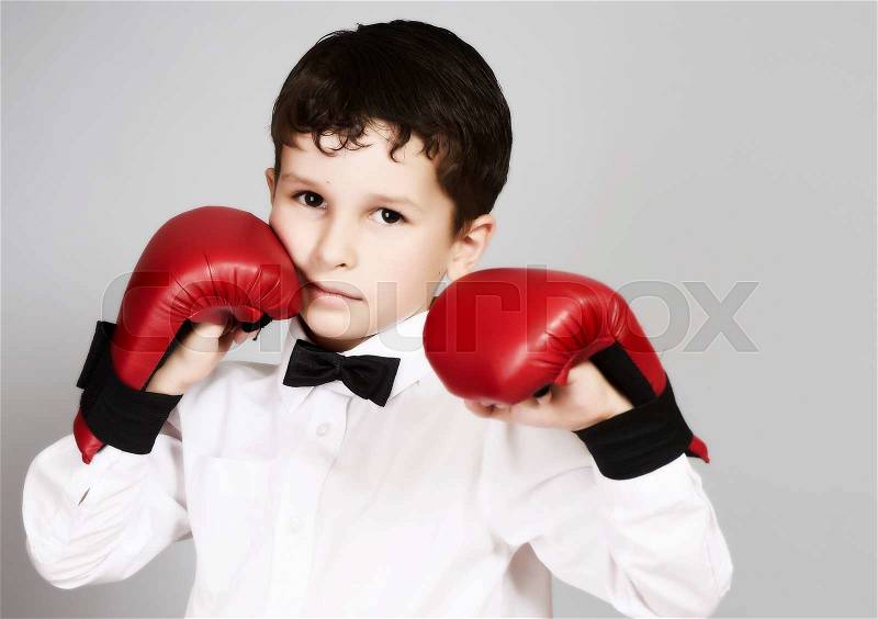 Five years old boy in white shirt and bow tie with boxing\karate gloves on the hands, stock photo