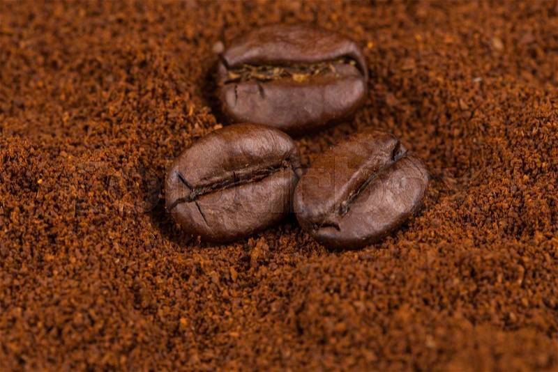 Coffee beans on heap of ground coffee close-up, stock photo