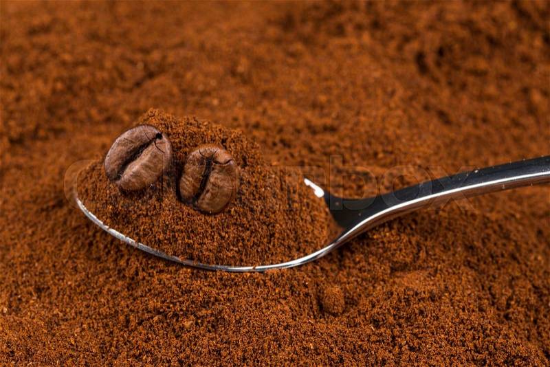 Pile of ground coffee and a metal spoon close up, stock photo