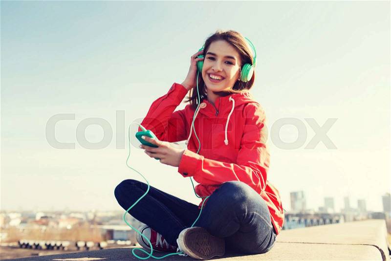 Technology, lifestyle and people concept - smiling young woman or teenage girl with smartphone and headphones listening to music outdoors, stock photo